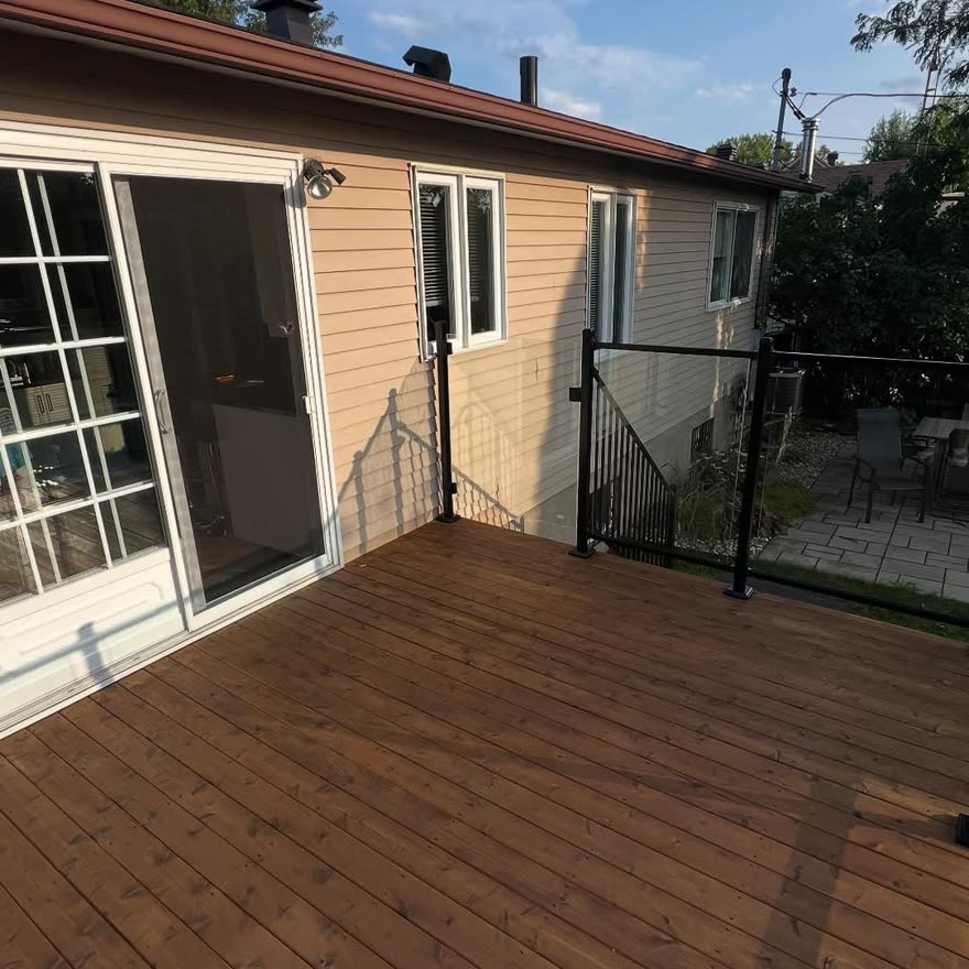 Grande terrasse en bois avec garde-corps devant une porte-patio
